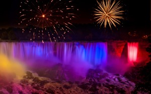 Niagara Falls at night in rainbow colors with fireworks